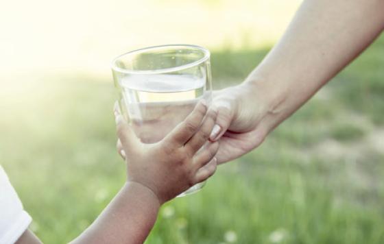 Handing a glass of water to a child. Photo credit: iStock