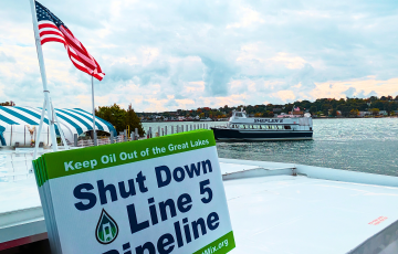 Shut Down Line 5 Pipeline sign held on a boat in the Mackinac Straits between Lake Michigan and Lake Huron